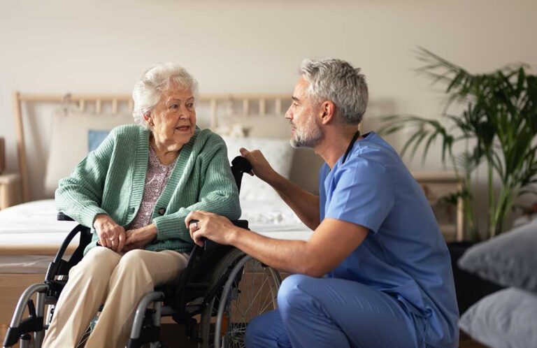 Two assisted living residents and a caregiver smiling together at a dining table
