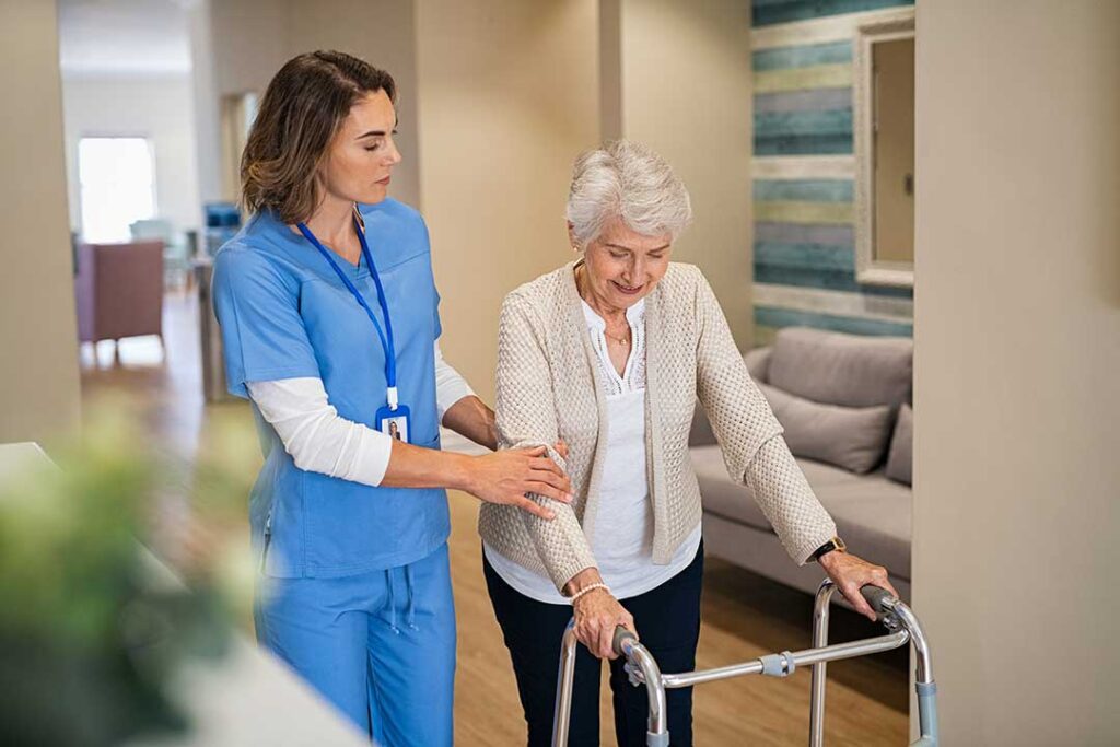 Older adult and family member organize labeled clothing, toiletries, and photos in an assisted living room.